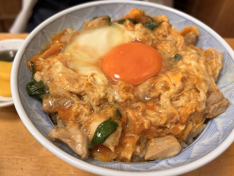 半熟の卵と鶏肉を重ね、真ん中に卵黄を落とした親子丼のアップ